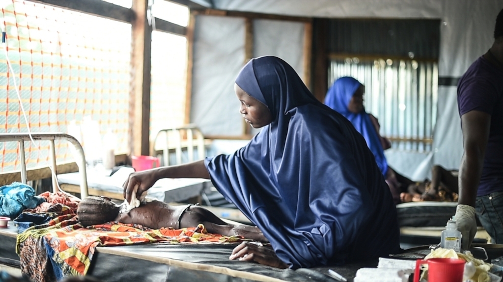 A mother places a cool, damp washcloth on her daughter's body to bring her fever down in the isolation ward of the general hospital in Damboa, Borno state, Nigeria. Her daughter is being treated for measles with complications. The most severe cases are referred to the hospital in Biu, two hours' drive away. Photographer: Ikram N'gadi/MSF