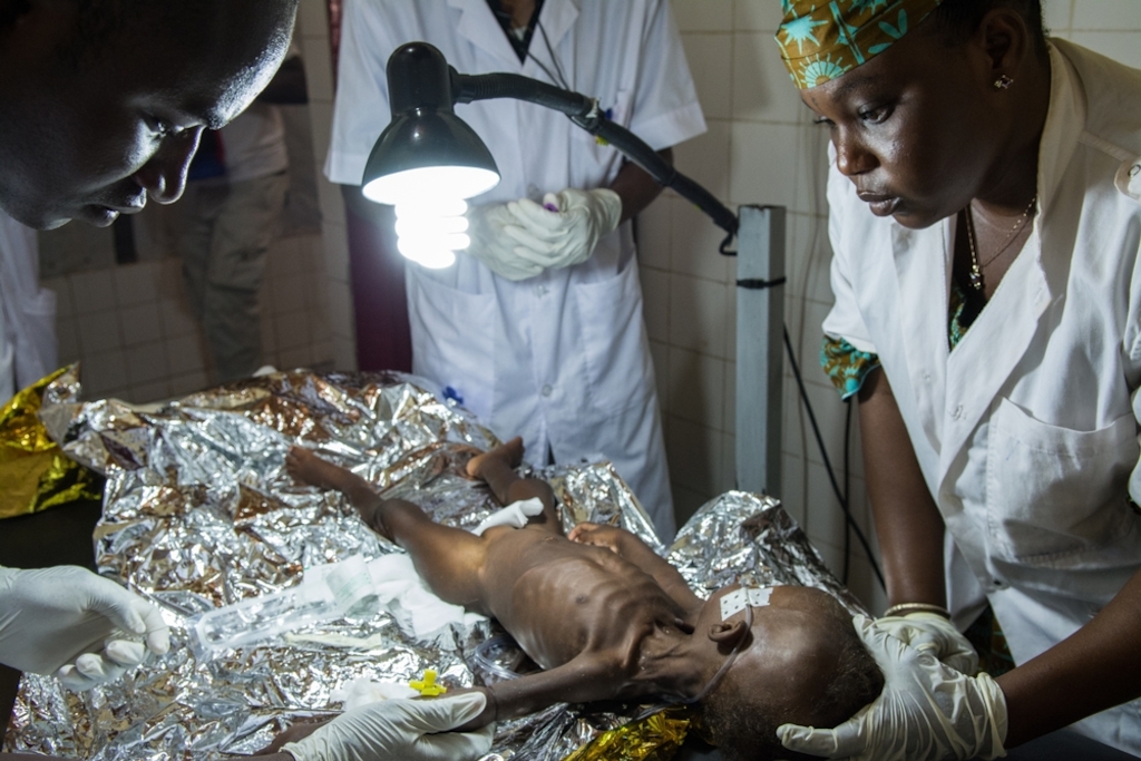Health workers examine a child with suspected malnutrition and malaria in an MSF-supported hospital in the Magaria region in southern Niger. The rainy season corresponds to the lean season, so malaria and malnutrition peaks coincide. For children in particular, this period of the year represents a real fight for survival. Photographer: Louise Annaud/MSF