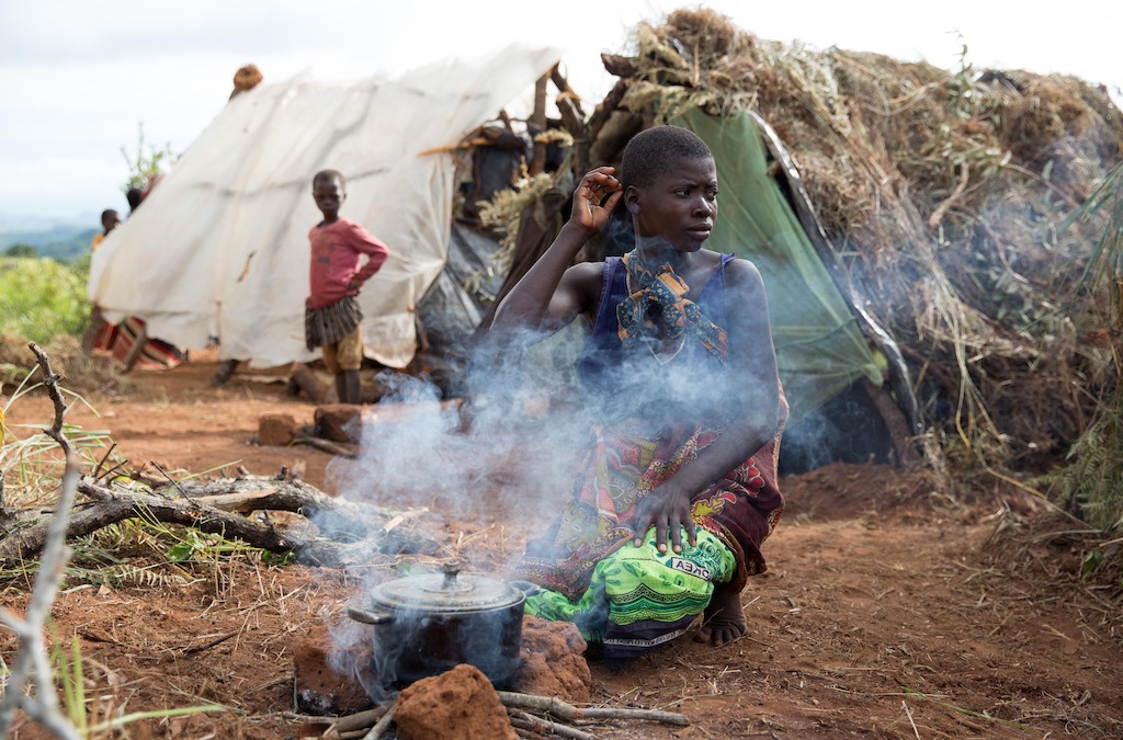 A 22 year old woman tends to a fire. Over 5.800 Mozambican nationals have camped in the village of Kapise 2 in Malawi after fleeing their homes in Mozambique. The overcrowding and the nature of the makeshift constructions in the camp, made of foraged wood and grass, make it a fire hazard. © James Oatway / MSF