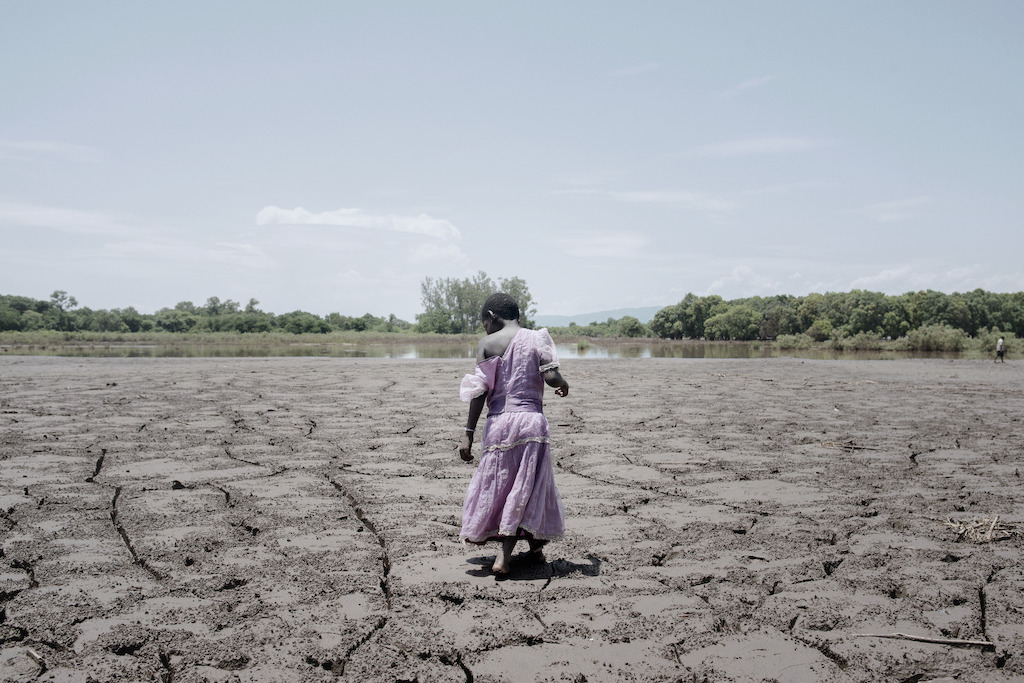 © Luca Sola<br/>Alesi Phiri, 7 ans, enjambe un vaste champ de boue séchée. Au début de l’année 2015, le Malawi a été victime d’énormes inondations. L’eau et la boue ont laissé derrière elles des champs détruits, une catastrophe pour une région où 85% de la population vit de l’agriculture.