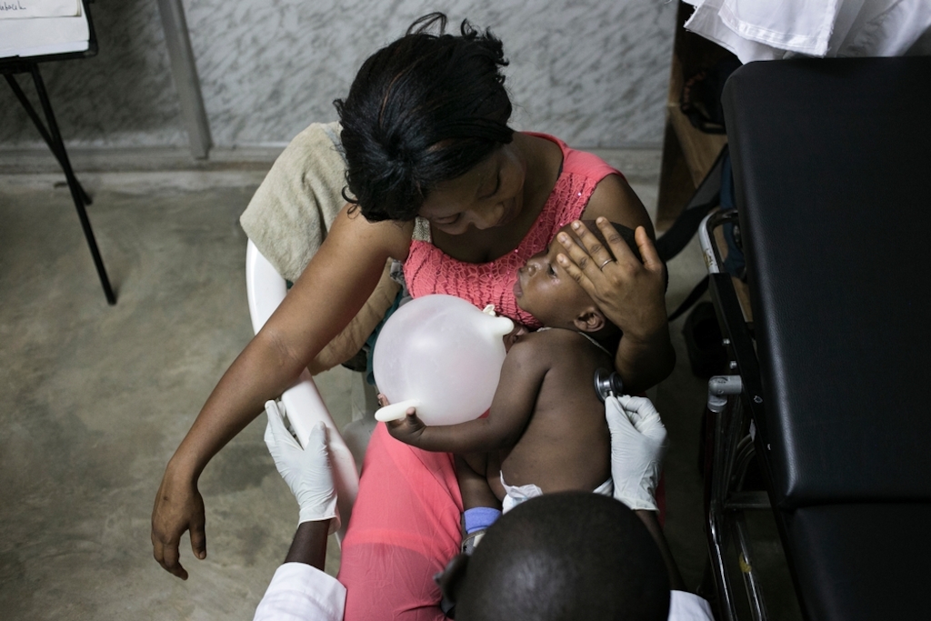 14 month old M'Bemba with his foster mother and aunt Fatoumata Eisse during a medical consultation with Dr Daouda Berete at the Medecins Sans Frontieres (MSF) health facility in Nongo, Conakry. Photographer: Albert Masias/MSF