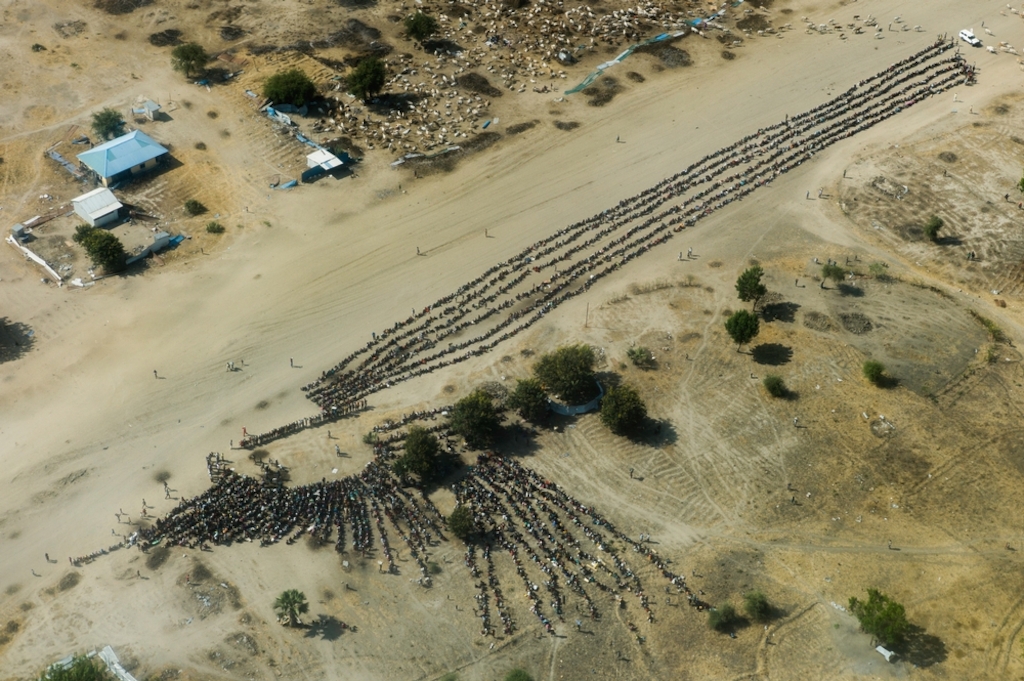 Lines of displaced people wait for an aid distribution in the otherwise empty and destroyed town of Leer, Unity state. Many thousands of people fled fighting in the area, seeking safety in the surrounding bush and swamplands or in the UN compound. Photographer: Dominic Nahr