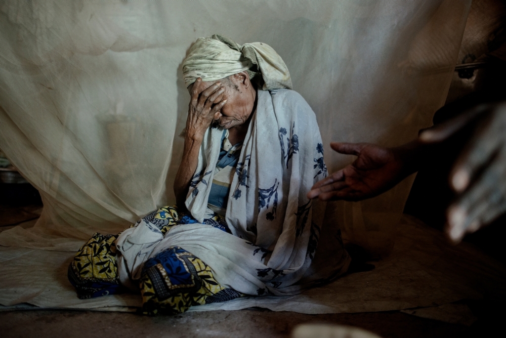 MSF159642<br/>65 year old Amine at a at a camp for displaced people at the Central Mosque in Bangui.<br/><br/>Amina is from Bouca in the north of the country. One morning around 5am, armed groups surrounded her neighbourhood and pushed all Muslims inside a house and then set the house on fire. Amina was in a neighbour’s house watching the scene from the window. She was saved thanks to a Christian who protected and allowed her and some other mothers to escape. Amina found her four daughters and fled. One of her daughters paid for a ticket to go to Bangui while her daughters fled to Chad. That was three years ago, Amina often calls her daughters who now live in a refugee camp in Chad. Hachta (40), Apsita (35) and Kadidja (28) are healthy but have not been able to find work. Mariam (30), her fourth daughter died at his arrival in the camp following an illness. Amina would like to join her daughters but due to lack of money, she cannot. Today Amina survives thanks to the solidarity of the displaced families in the mosque, and the distribution of food in the camp.