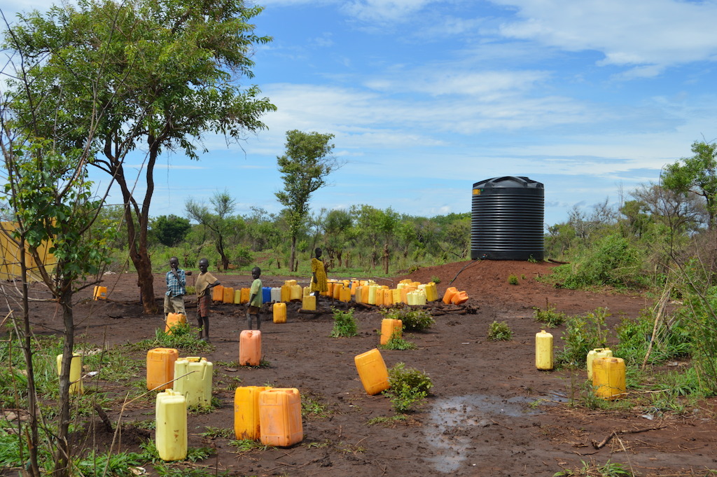 Refugees gather to collect water at one of the water tanks in Palorinya refugee settlement. <br/>MSF produces an average of 2 million litres per day from the Albert Nile River, which is delivered to tanks throughout the settlements by water trucks rented by UNHCR. Bad road conditions make it difficult for trucks to access all areas of the settlements after heavy rains, leaving several areas vulnerable to water shortages. <br/>By 5 May 2017, there were over 901,755 South Sudanese refugees in Uganda, with the number expected to rise to nearly one million by the end of the year. Some 86% of the South Sudanese refugees in Uganda are women and children under 18, and an average 2,000 new refugees arrive each week. Uganda is now the largest hosting country for South Sudanese refugees, and also the country hosting the largest population of refugees in Africa. Photographer: Yuna Cho/MSF