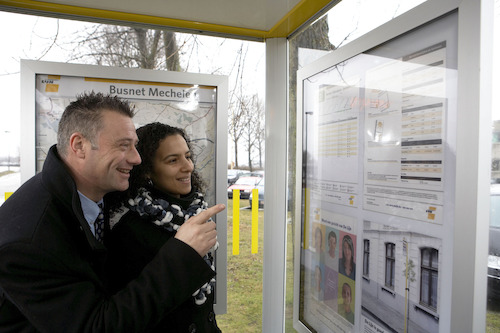 Reizigers raadplegen een dienstregeling in een schuilhuisje van De Lijn<br/>Foto: Stefaan Van Hul