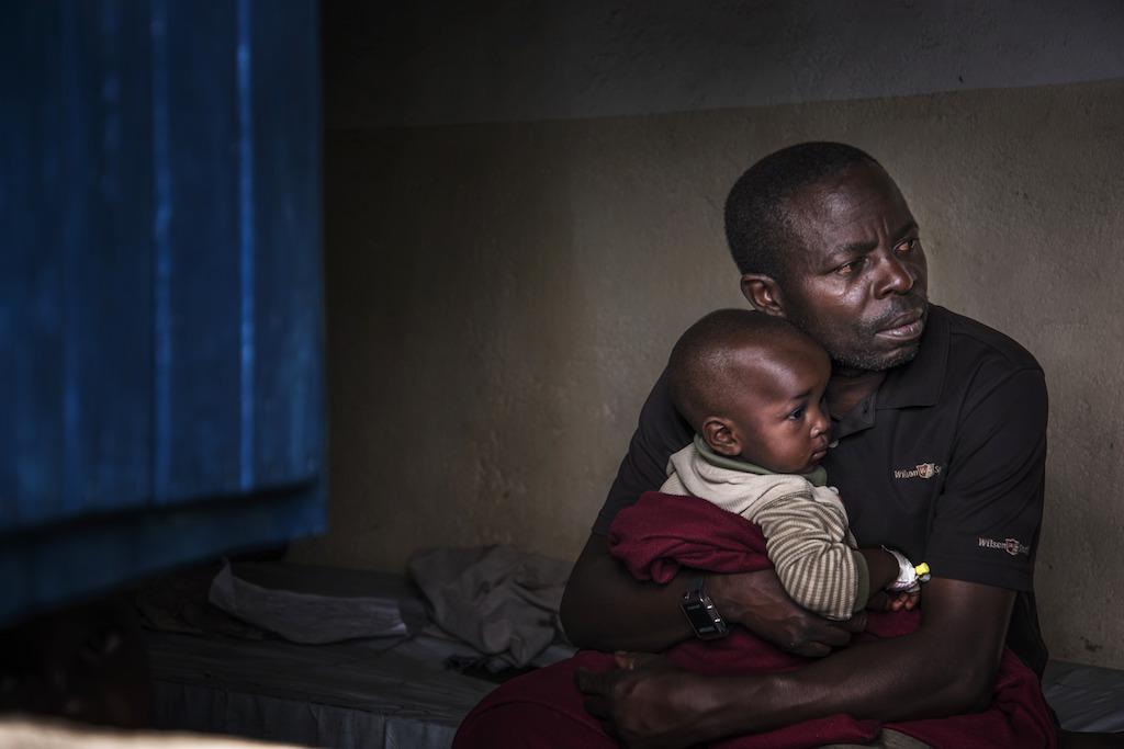 A father holds his son who is gradually recovering from cholera. Photographer: Arjun Claire