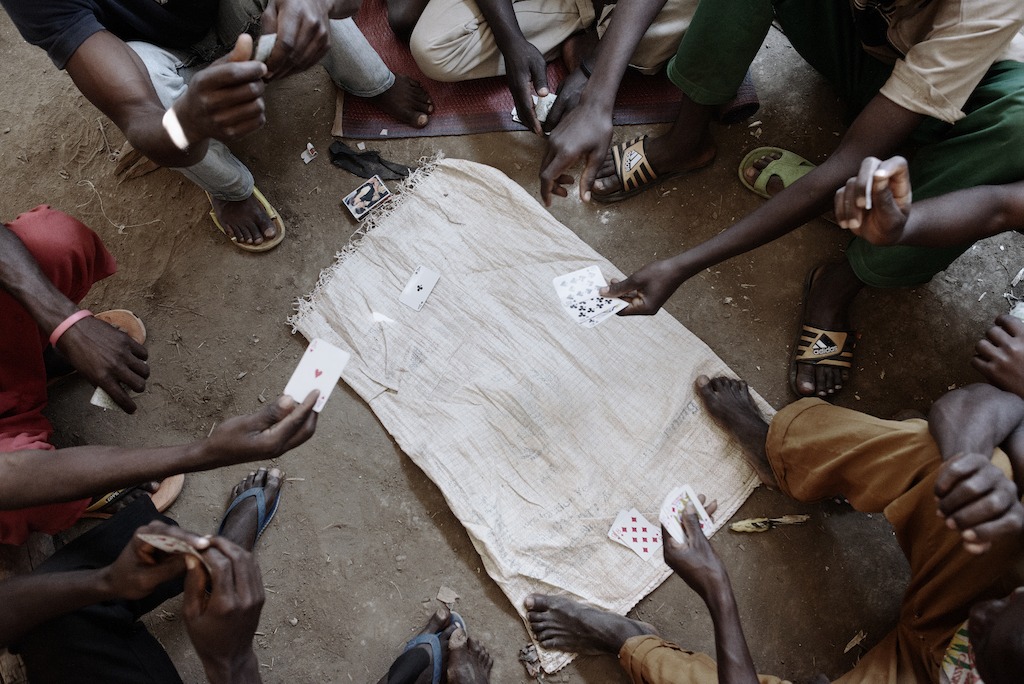 Refugees gather to play cards inside one of the mass shelters in Nyarugusu camp. The shelters were built to house 200 people, but in some cases, they host up to 370. Photographer: Luca Sola