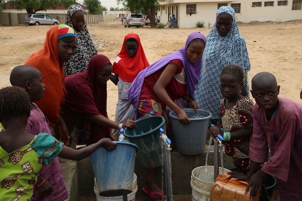 Nigerian women and children displaced by the conflict between Boko Haram and the Nigerian armed forces fetch water in the town of Banisheikh. Photographer: Igor Barbero