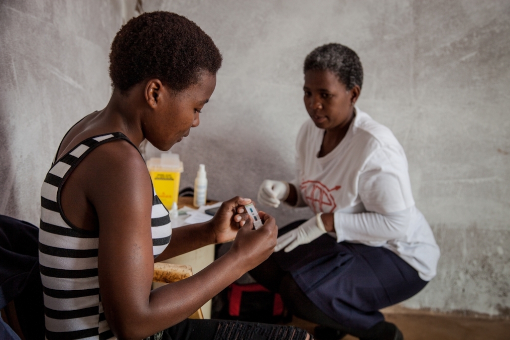 Community Health Agent Babongile Luhlongwane conducts an HIV test on Andile (28), who lives in the remote Entumeni District of KwaZulu-Natal, where HIV prevalence in South Africa is among the highest. If he tests positive, she will refer him to the nearest local clinic to be initiated onto ARVs. Babongile is one of nearly 90 dedicated health workers who are taking HIV counselling and testing to the most remote parts of KwaZulu-Natal. She says she enjoys teaching people how HIV works, and helping them to start on treatment if necessary. Photographer: Greg Lomas / Médecins Sans Frontières