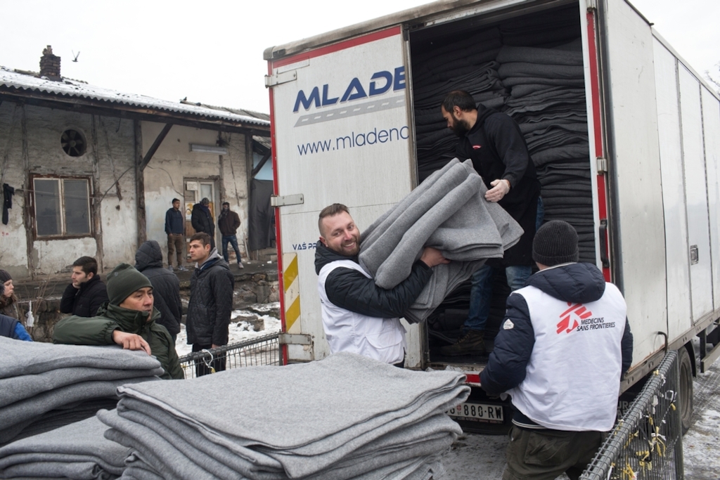 Igor Kuhar, center, and Goran Bakic, right, Medecins Sans Frontieres (MSF) staffers, unload blankets from a truck while distributing aid to refugees in Belgrade, Serbia. Photographer: Marko Drobnjakovic