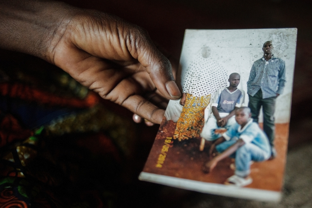 MSF159645<br/>Alima shows a photograph of her son, Amousa who was 23 years old at the time of his death (right, 1st row)<br/><br/>He was treated at the Red Cross Center after he became ill due to the living conditions in the camp.<br/><br/>Alima is trying to cope by relying on the help of other people living with her in the camp, as she and her husband are unemployed. “We were born here, our parents and grandparents too... and now we are treated as strangers".