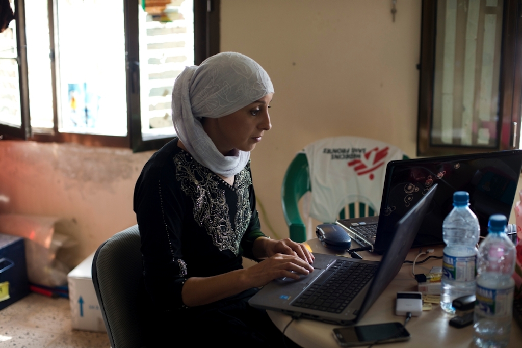 MSF Doctor Nora Echaibi works<br/>on logistics and budget for the day at the<br/>office, on July 22, 2015. MSF supports a<br/>couple of health facilities and hospitals in<br/>Qataba with international staff, medication, extra local staff support, and equipment.<br/>Photo credit: Alex Potter