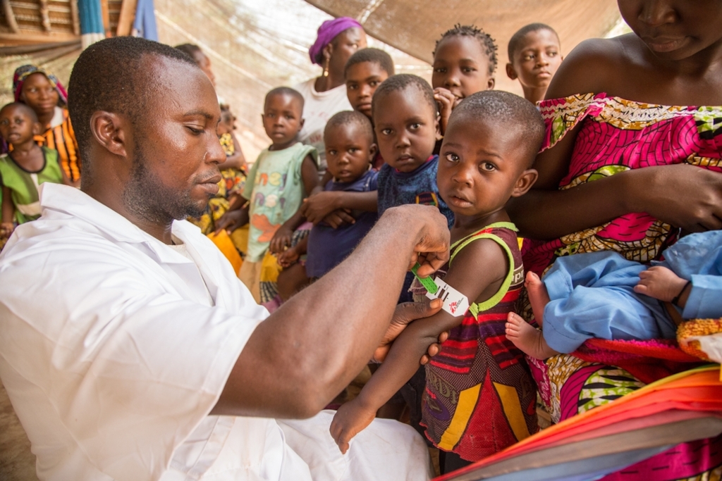 Children crowd around as an MSF health worker screens a young boy for malnutrition at the start of a mass vaccination campaign in Central African Republic. Photographer: Pierre-Yves Bernard/MSF