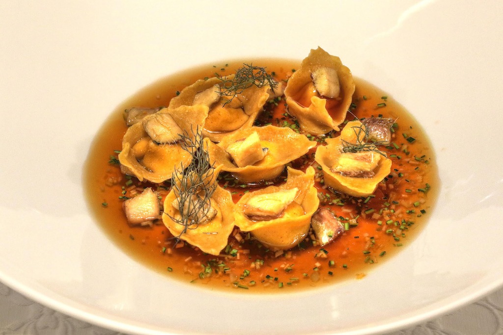 Ravioli di farina di polenta con ricotta Piemontese il pesce agone alla brace in consommé di pesce alla soia