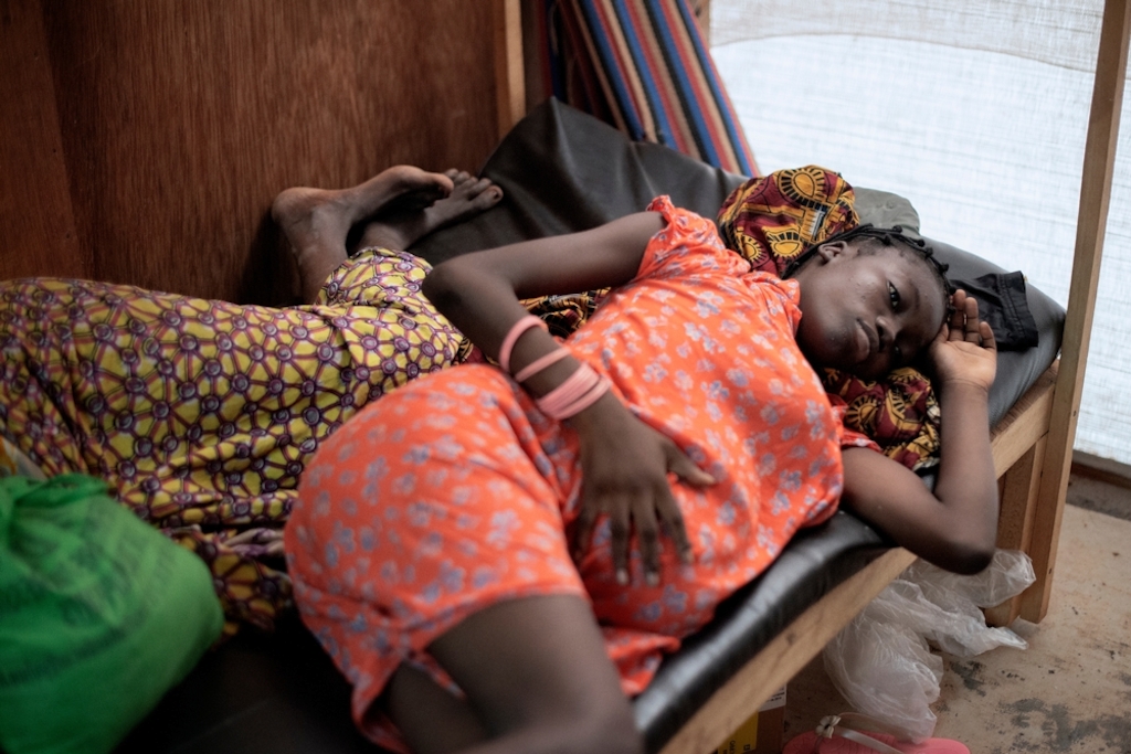 16 year old Naomi waits to be seen at a Medecins Sans Frontiers (MSF) hospital at a displaced persons camp in M'Poko, Bangui.<br/><br/>Naomi will give birth to her first child at the MSF maternity ward in Mpoko camp. When her father died, Naomi was sent by her mother to study in Garoua Boulai in Cameroon, where some of their family members live. This is where she met the father of her child. To be with her family when the baby arrives, Naomi travelled for nearly a month to reach Bangui. The whole family, including her grandmother, her aunts and her mother, gathered in the MSF hospital to await the arrival of the baby. Photographer: Luca Sola