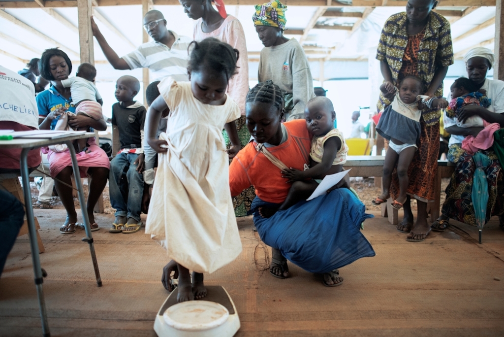 A child is weighed at a Medecins Sans Frontiers (MSF) hospital at a displaced persons camp in M'Poko, Bangui. Photographer: Luca Sola