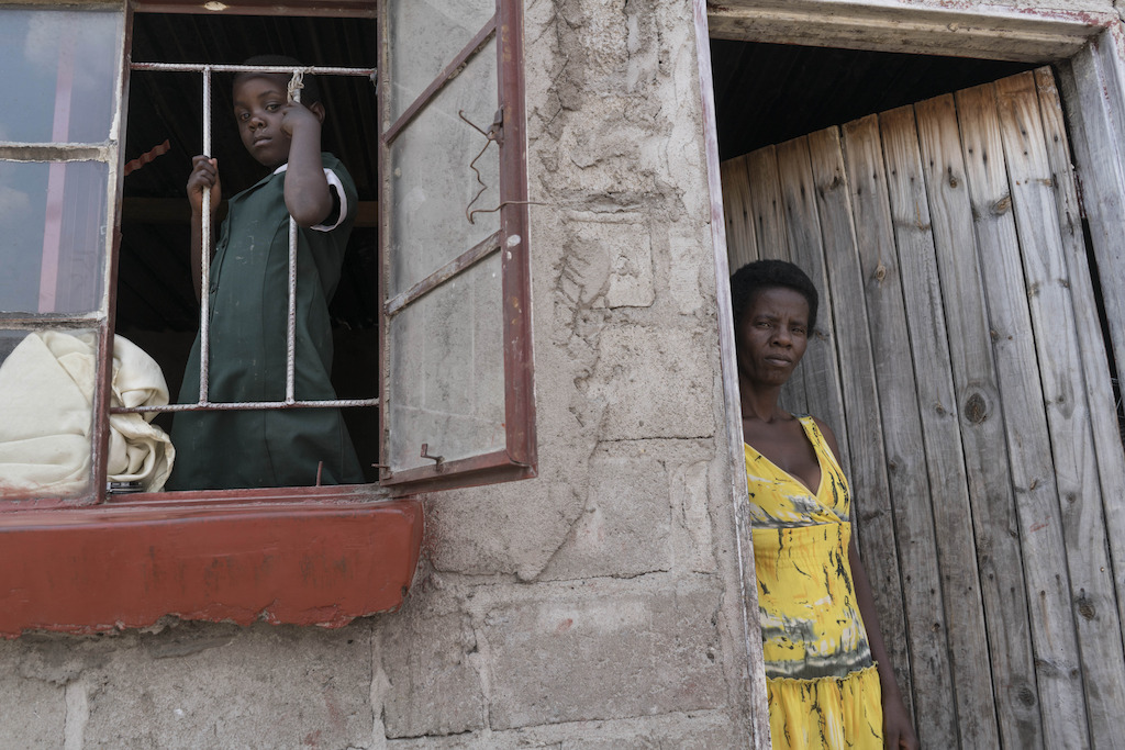 Five year old Shamiso looks through the window of her home after returning from school, alongside her mother, Prisca, at her modest one room home in Epworth on Harare’s outskirts. <br/><br/>44 year old Prisca started HIV treatment in 2008. Prisca joined the Epworth HIV program in 2011. Her daughter, Shamiso was born in January 2011, while her mother was part of the Prevention of Mother to Child Transmission program (PMTC). As a result, Shamison was born HIV negative. Photographer: Rachel Corner/De Beeldunie