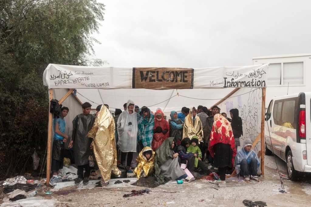 Photographer: Alessandro Penso<br/><br/>Caption: Refugees take shelter during a rain storm as they wait to be registered at the Moria Reception Centre in Lesbos, Greece.