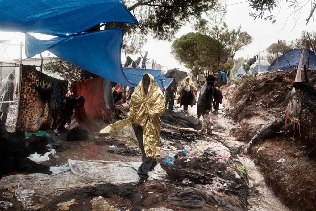Photographer: Alessandro Penso<br/><br/>Caption: Refugees and migrans walk along a muddy path, lined with rubbish as they wait to be registered at the Moria Reception Centre in Lesbos, Greece.