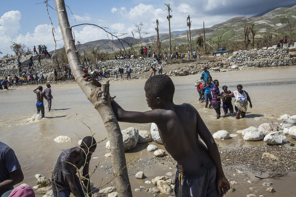A collapsed bridge at Roche-a-Bateau means people must cross through the river on foot, in southwestern Haiti. Hurricane Matthew tore through the Caribbean on October 4 and devastated large parts of the island. Photographer: Andrew McConnell/Panos Pictures