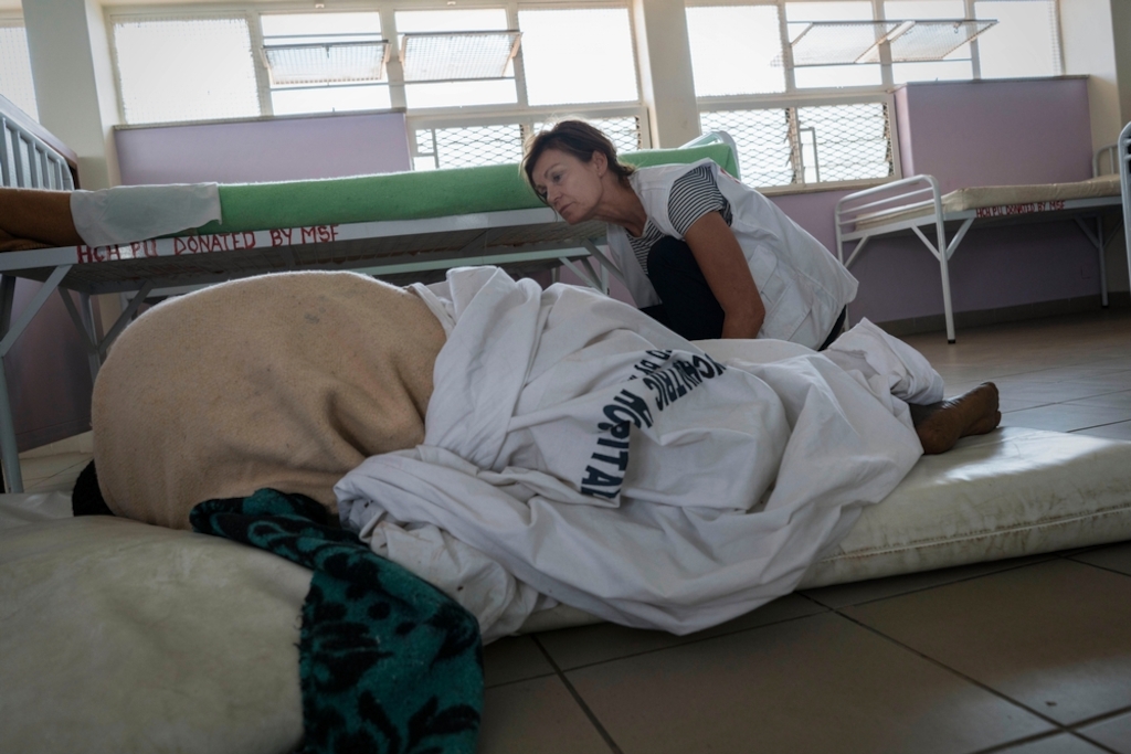 Linda Buijze, MSF nurse activity manager, a trained psychiatric nurse, checks a patient in the mental health hospital run by MSF. The patient lies on the ground so she can’t fall out of the bed. Rachel Corner/De Beeldunie