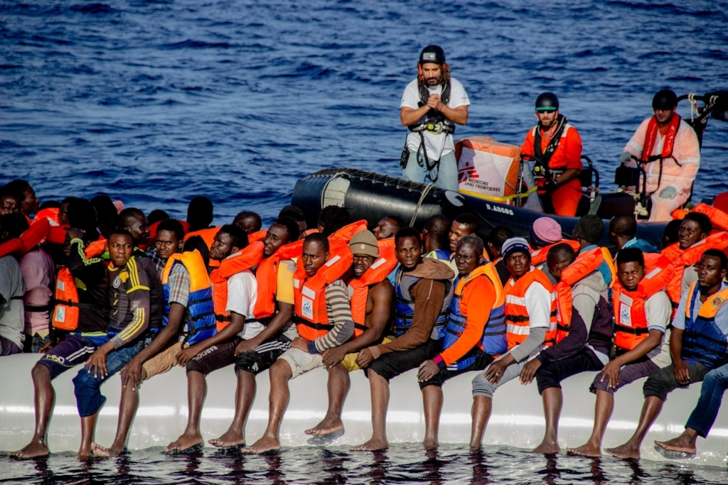 Firas Hebili, an MSF cultural mediator, talks to people crowded on board a rubber dinghy during a rescue off the northern coast of Libya. Photographer: Borja Ruiz Rodriguez/MSF