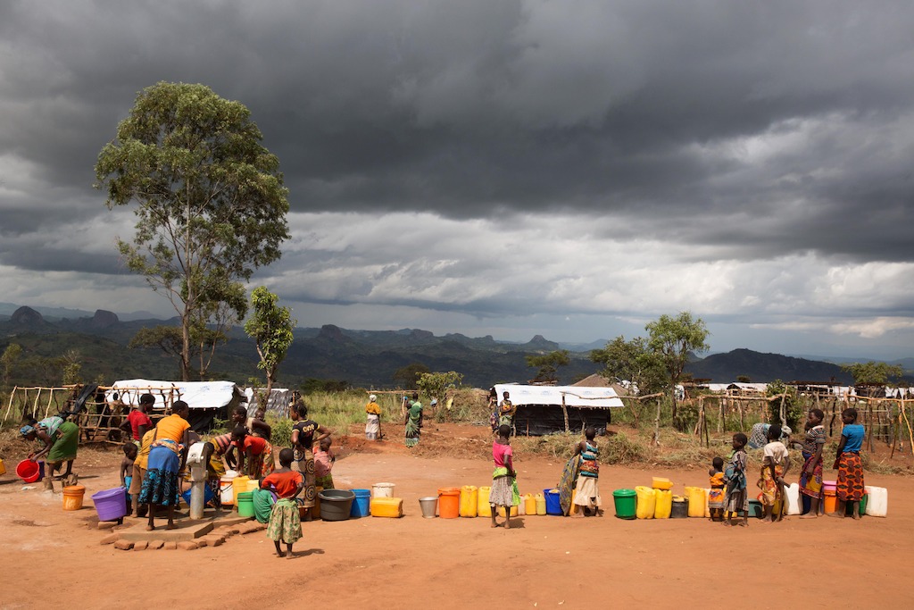 People queue at an Medecins Sans Frontiers (MSF) built water pump. Over 5.800 Mozambican nationals have camped in the village of Kapise 2 in Malawi after fleeing their homes in Mozambique, the majority of them women, children and the elderly. The only regular water source in the village has ran dry and the only way to get water is from few pre-existing sources and the two additional boreholes respectively rehabilitated and constructed by MSF. Even then, waiting times up to 2.5 hours at the water pump and with the continuous influx of people, the capacity of the borehole today can only provide around 8 liters of water per person per day, well below the minimum humanitarian standards of 15-20L. © James Oatway / MSF