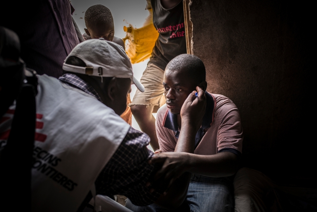 An MSF health worker communicates with an HIV-positive man who became deaf and blind after he stopped taking his antiretroviral drugs due to social stigma. MSF teams go door-to-door to test people for HIV in Katwe, Uganda. Photographer: Guillaume Binet/MYOP