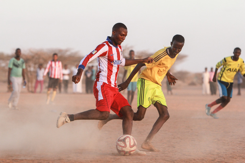 MSF national staff (in red) play soccer with the refugee residents of Dagahaley, in Dadaab refugee camp, Kenya. Photographer: Tom Maruko