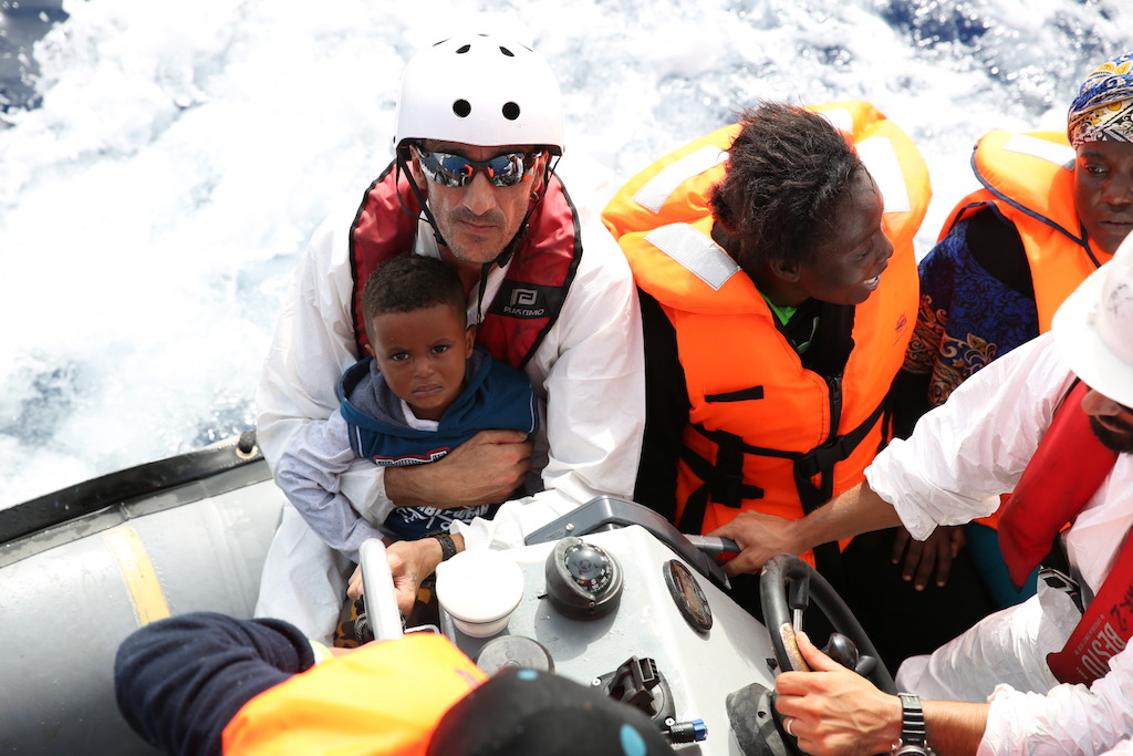 A member of the crew holds a little boy on 16 October. A large number of the rescued people are minors. They often sit along with the mothers in the middle of the flimsy boats, so if a crack appears they are in the most vulnerable position. Photographer: Mohammad Ghannam