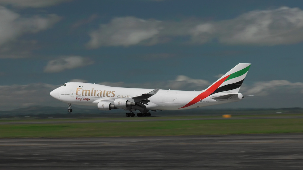 Emirates SkyCargo freighter taking off from Auckland with Emirates Team New Zealand's boat