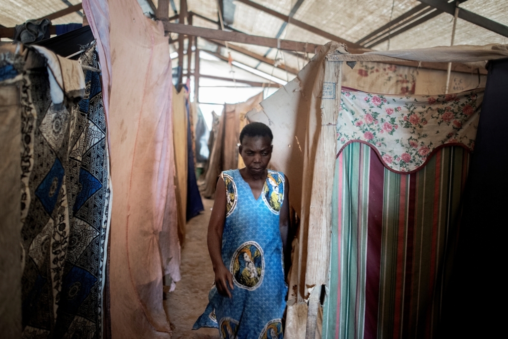 MSF159669<br/>45 year old Julienne walks inside a shelter at a displaced persons camp in Benzvi, Bangui.<br/><br/>Julienne has lived in Benzvi camp for one year but it has been two years since she left her arrondissement near KM5 in Bangui. An armed group came into her house but she escaped with her seven children, her husband and her grandson. While they were fleeing, her grandson was shot and died, just as they arrived in the camp of Saint Jacques. They stayed more than a year in this structure but they finally decided to move again because of lack of space in the church. She has to look after children on her own. In order to survive, she receives food rations from NGOs. <br/>Julienne doesn’t want to return to her neighbourhood. Her house was burned and looted and her safety cannot be guaranteed.