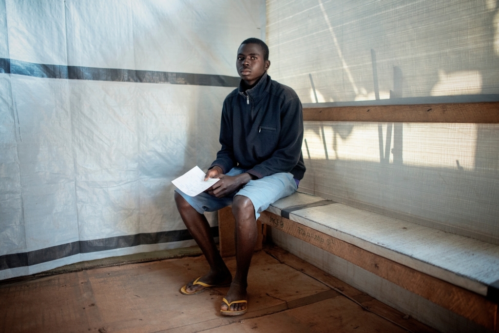 MSF159680<br/>20 year old Stéphane waits to be seen at a Medecins Sans Frontiers (MSF) hospital at a displaced persons camp in M'Poko, Bangui.<br/><br/>"When there is gunfire or grenades, I can not go to school" says Stephane, who has lived in Mpoko Camp for two years. He had to flee his district, the 3rd arrondissement of Bangui, after a group of men burned his house and all the possessions of his family. Stéphane is a high school student and is the only person in his family that can earn money to support his five family members. Sometimes, he works as a daily worker at MSF’s clinic in Mpoko.