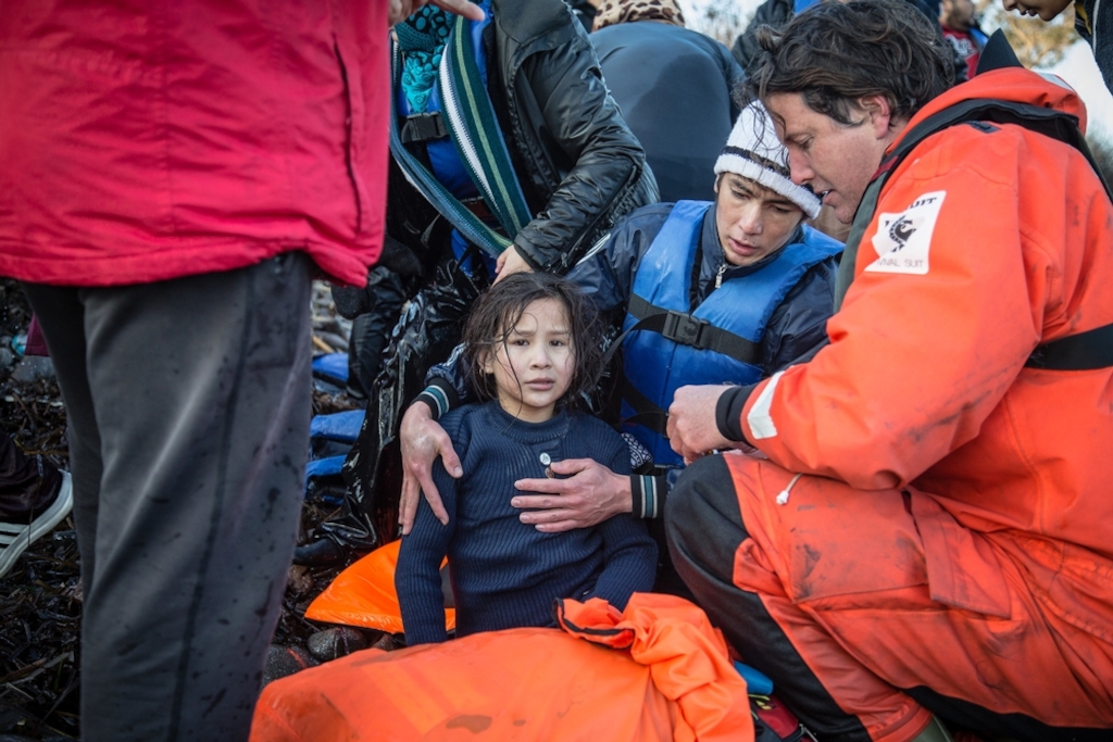 A father and daughter recover on a beach on the island of Lesbos after being rescued from a boat on the sea crossing from Turkey. Joint MSF and Greenpeace crews are assisting boats in distress off the coast of Lesbos alongside the Greek coastguard. Photographer: Will Rose