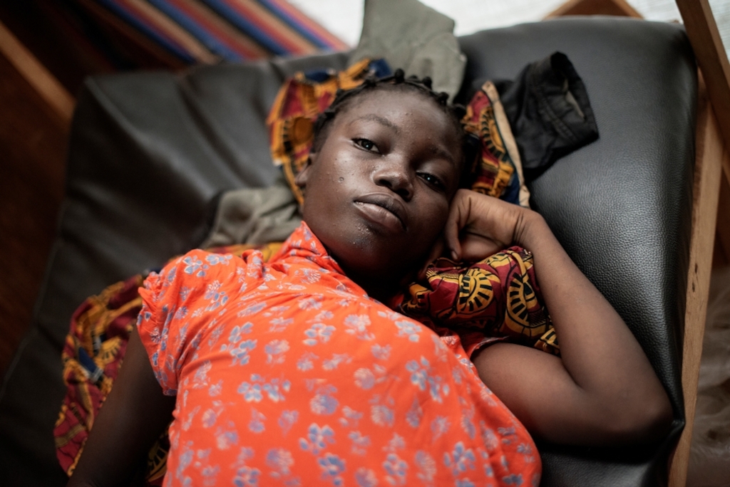 MSF159683<br/>16 year old Naomi waits to be seen at a Medecins Sans Frontiers (MSF) hospital at a displaced persons camp in M'Poko, Bangui.<br/><br/>Naomi will give birth to her first child at the MSF maternity ward in Mpoko camp. When her father died, Naomi was sent by her mother to study in Garoua Boulai in Cameroon, where some of their family members live. This is where she met the father of her child. To be with her family when the baby arrives, Naomi travelled for nearly a month to reach Bangui. The whole family, including her grandmother, her aunts and her mother, gathered in the MSF hospital to await the arrival of the baby.
