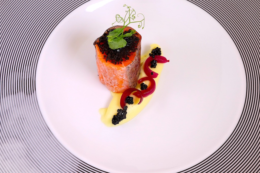 Filetto di trota affumicata su patate all'olio di oliva con cipolla rossa in scapece, pane nero e caviale