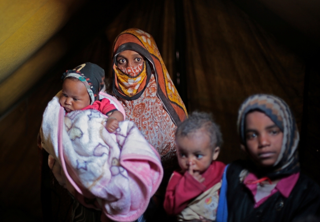 A woman and her children shelter in a camp on the outskirts of Amran, in northern Yemen, for people displaced from their homes by fighting between Houthis and the Saudi-led coalition. Photographer: Rawan Shaif
